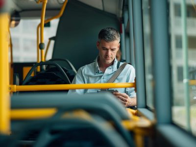 Confident businessman traveling by bus and using a digital tablet